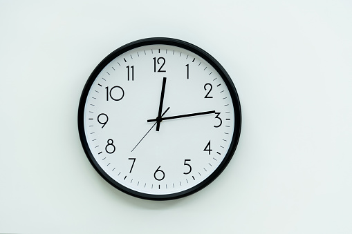 Black wall clock on white background.
