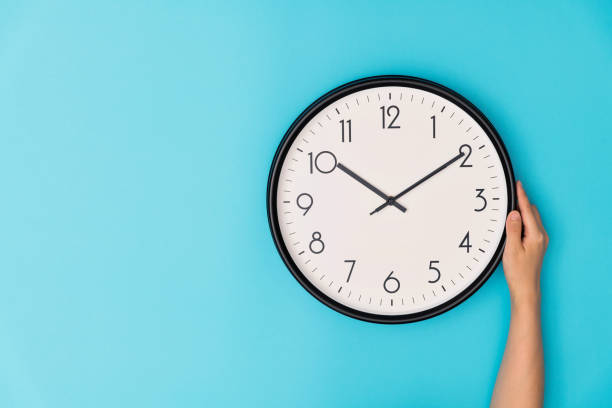 main humaine retenant une horloge sur le fond bleu - clock time clock hand urgency photos et images de collection
