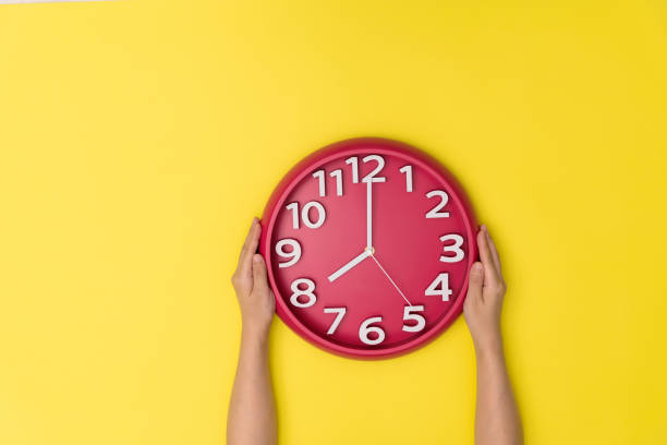 main humaine retenant une horloge sur le fond jaune - clock time clock hand urgency photos et images de collection