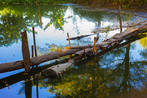 Wooden bridges for pathways across waterways are simply built according to the way of life of the rural people with the reflection of the trees on the water.