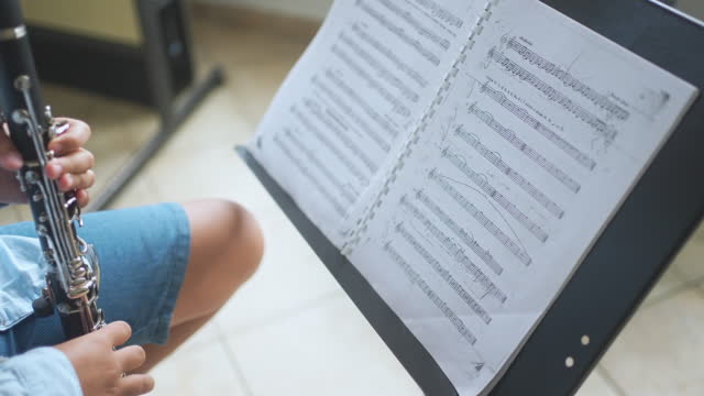 Child Playing Clarinet And Turning Page To New Exercises