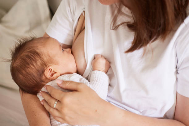 matka karmiąca piersią swojego nowo narodzonego synka. realistyczny portret domowy - mleko z piersi zdjęcia i obrazy z banku zdjęć