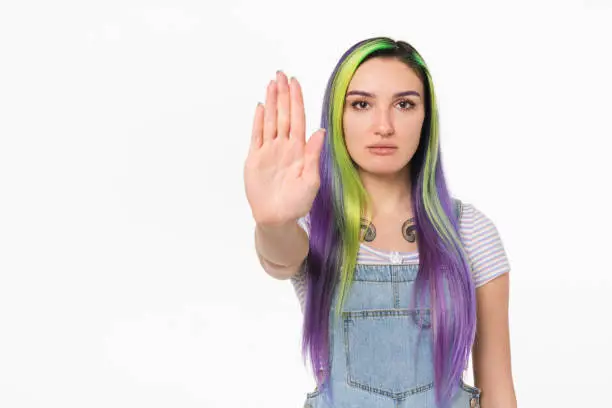 Photo of Young caucasian teenage girl woman hipster showing stop gesture sign with her palm isolated in white background. Forbidden, prohibited concept