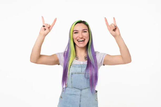 Happy cheerful caucasian young teenage woman hipster dancing on rock concert showing rock-n-roll gesture isolated in white background