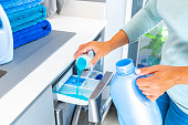 istock Woman adding fabric softener or detergent to a washing machine 1413851648