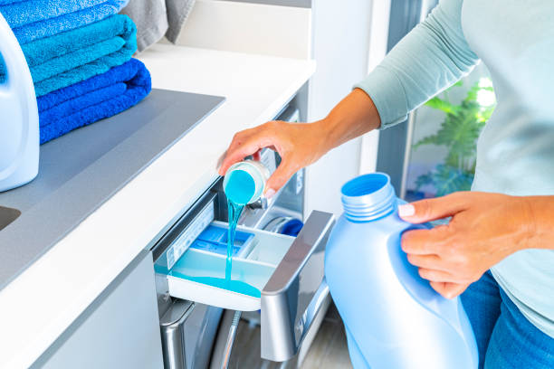 Woman adding fabric softener or detergent to a washing machine Close up of woman hands adding fabric softener or detergent to a modern washing machine.  High resolution 42Mp indoors digital capture taken with SONY A7rII and Zeiss Batis 40mm F2.0 CF lens laundry detergent stock pictures, royalty-free photos & images