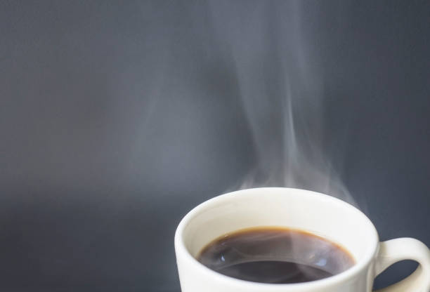 Hot coffee with smoke ready to drink on a gray background with empty space.