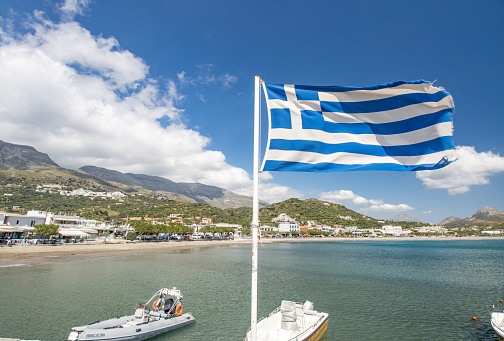 Greek Flag at Plakias in Municipality of Agios Vasileios on Crete, Greece, with boat names in the background.
