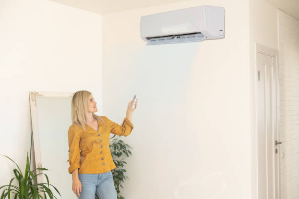istock Air conditioner inside the room with woman operating remote controller. Air conditioner with remote controller 1413854757
