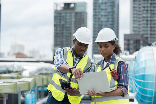 istock Group of African American engineer worker working in sewer pipes area at construction site. Male engineer and woman engineer work with laptop computer for maintenance sewer pipes, water tank 1413854821