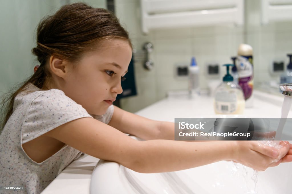 We must wash our hands for at least 20 seconds Adorable little girl washing her hands in the bathroom. Responsible child with healthy daily habits. Virus infections prevention 4-5 Years Stock Photo