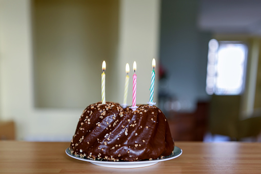 Birthday cake with colorful candles. Close-up picture of delicious small chocolate cake on the plate