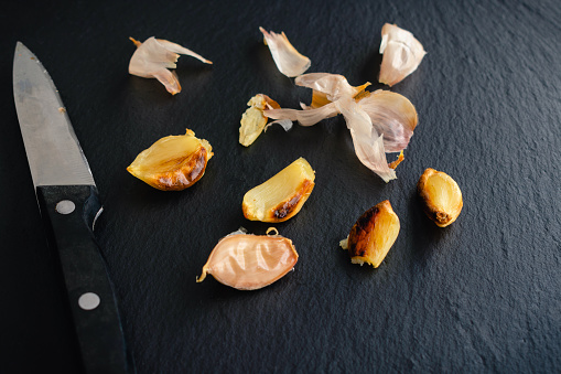 Peeled and unpeeled roasted garlic with a paring knife