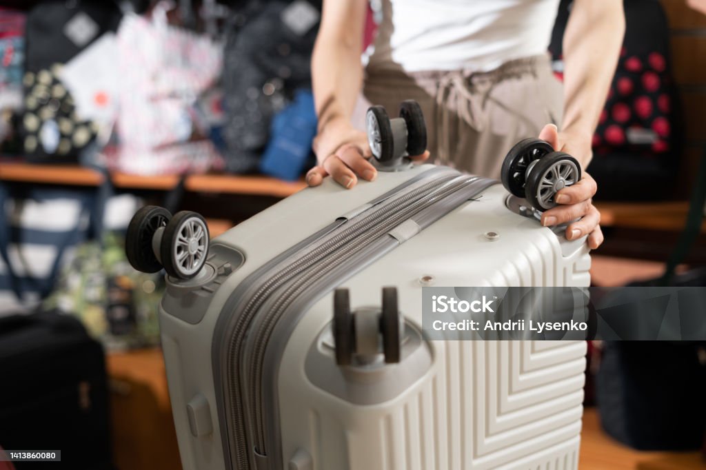 female customer choosing travel suitcase in haberdashery shop, wheels rollers suitcase female customer choosing travel suitcase in haberdashery shop, wheels rollers suitcase close-up Luggage Stock Photo