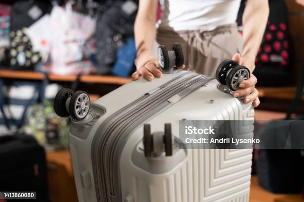 Female Customer Choosing Travel Suitcase In Haberdashery Shop Wheels Rollers Suitcase Stock Photo - Download Image Now