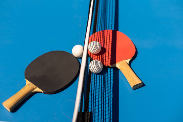 istock Table tennis rackets and a white plastic ball on a blue background. 1413861327