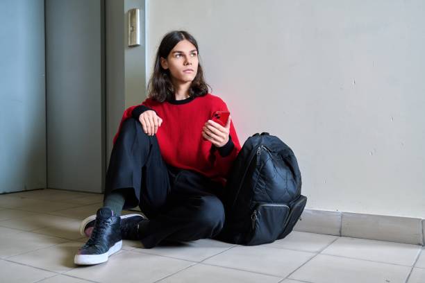 istock Sad teenage guy sitting on floor near elevator inside building 1413861700