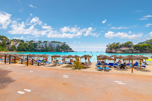 People relaxing in beach chairs at the Playa Cala Galdana Beach on the Southern side of the island of Menorca, part of the Balearic archipelago in the Mediterranean.