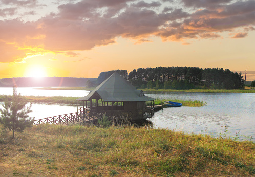 Wooden gazebo for fishing on the shore of Lake Seliger in the evening at a beautiful sunset. Ostashkov, Tver region, Russia