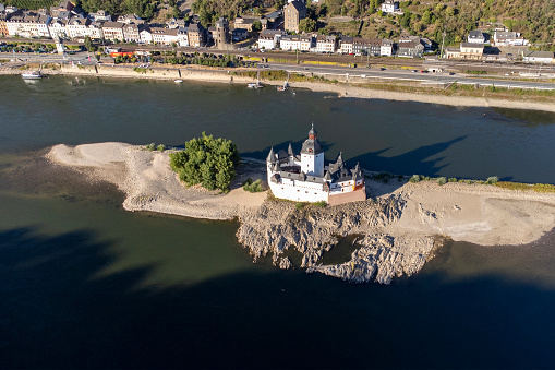 Kaub, Germany - August 08, 2022: Kaub and Burg Pfalzgrafenstein at Rhine valley. Visible rocks and sandbars due to extraordinary low water level after a long period of drought in 2022.