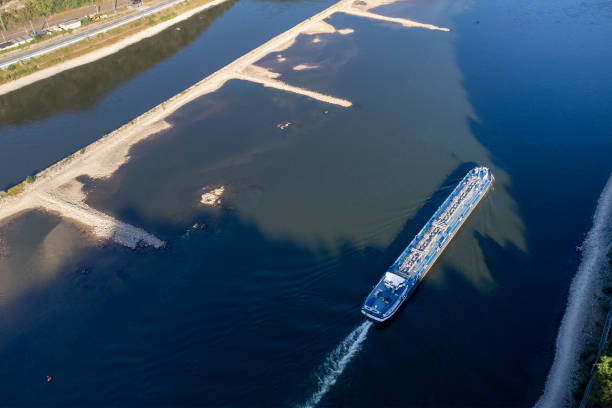 Industrial ship and low water level Industrial ship on Rhine river in the Rhine valley. Visible rocks and sandbars due to extraordinary low water level after a long period of drought in 2022. dry riverbed stock pictures, royalty-free photos & images