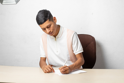 latin college student writing with pen. hispanic man
