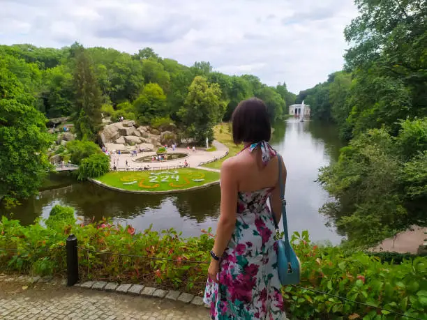 Landscape of Sofiyivsky Park, a botanical garden located in the City of Uman, Ukraine on a sunny summer day. Rear view of woman watching on the park from top. Popular tourist spot.