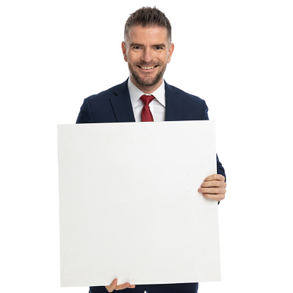 attractive businessman presenting his blank billboard and smiling at the camera against white background