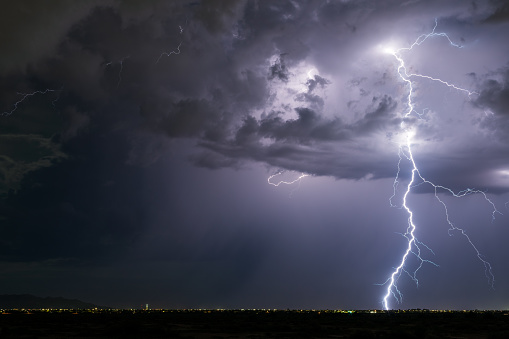 In a wild thunderstorm with high winds and pounding rain, lighting bolts strike repeatedly over cactus and junipers during a night time summer storm in southeast Colorado’s Comanche National Grasslands.