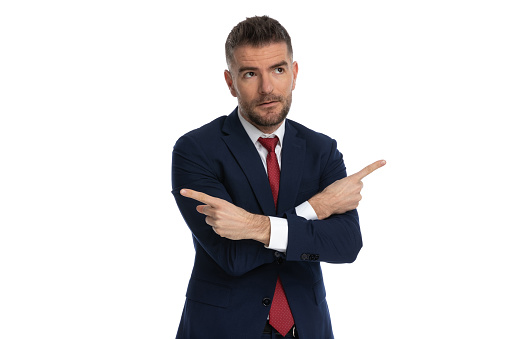 handsome businessman pointing in opposite directions and looking away against white background