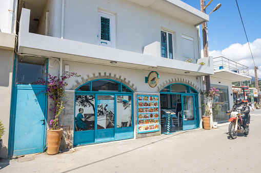 Commercial signs and people on scooters near a Restaurant at Plakias on Crete, Greece