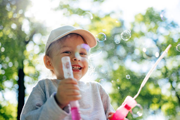 istock Little Girl Having Fun While Blowing Bubbles At Park 1413878499