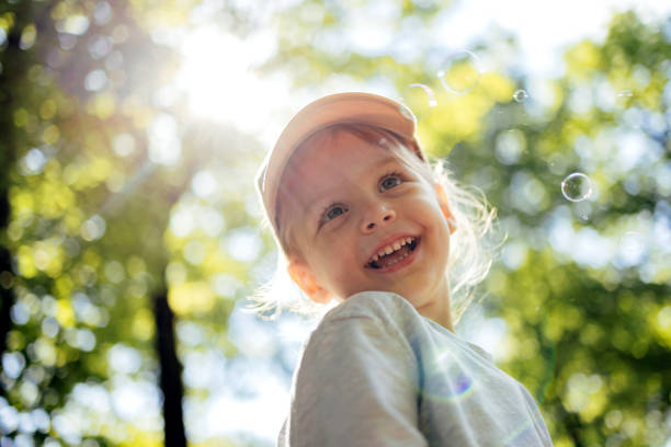 kleines mädchen, das spaß hat, während es blasen im park bläst - balloon child people color image stock-fotos und bilder