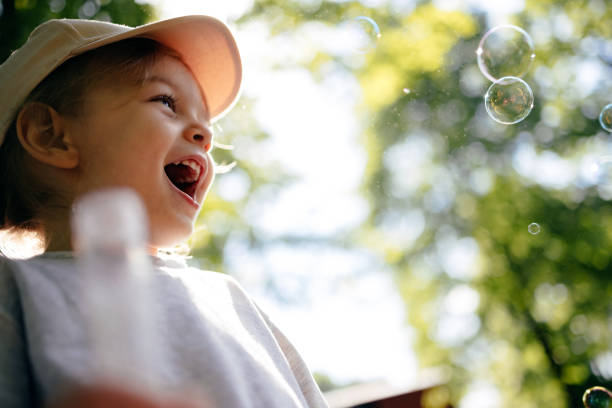 Low angle view of happy girl blowing bubbles outdoors.