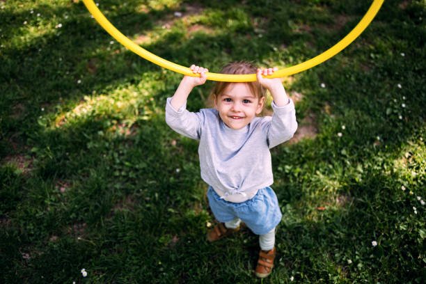 One girl, cute little girl playing with hoola hoop in living room at home.