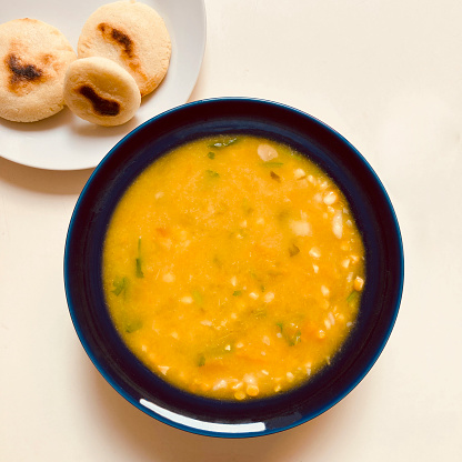 High angle view of vegetable soup made at home for lunch. 
Healthy eating or healthy lifestyle.Corn bread called also arepa in the upper left side of the image.