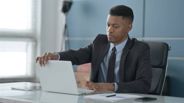 istock African Businessman Closing Laptop Standing Up, Going Away 1413882787