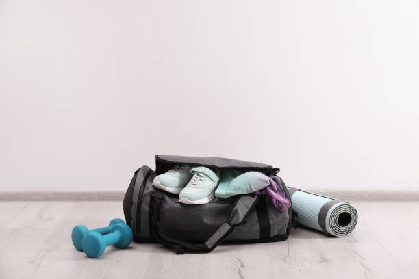 sac gris et accessoires de sport sur le sol près du mur blanc, espace pour le texte - gym bag photos et images de collection