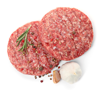 Raw hamburger patties with rosemary, garlic and spices on white background, top view