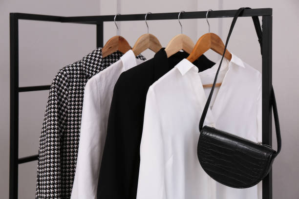 istock Rack with stylish women's clothes and bag near light wall 1413883987