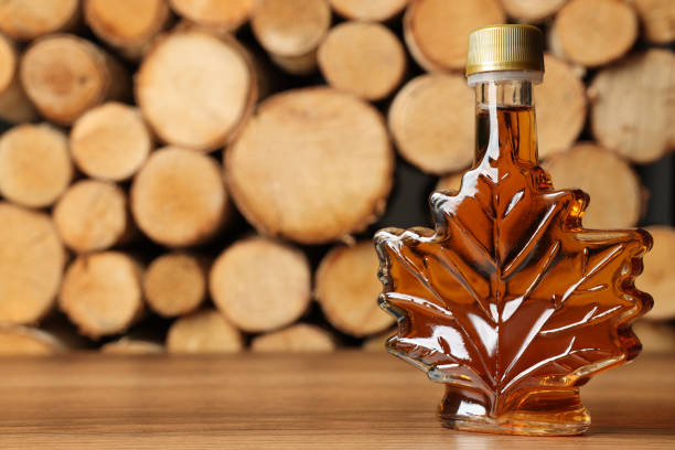 istock Leaf shaped bottle of tasty maple syrup on wooden table, space for text 1413883988