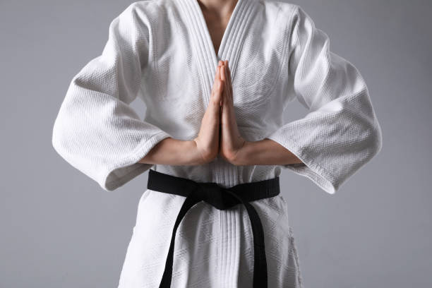 istock Martial arts master in keikogi with black belt on grey background, closeup 1413884753