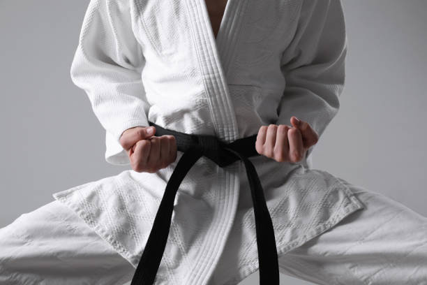 istock Martial arts master in keikogi with black belt on grey background, closeup 1413884906