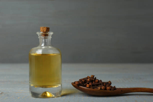istock Essential oil and dried cloves on grey wooden table. Space for text 1413885401