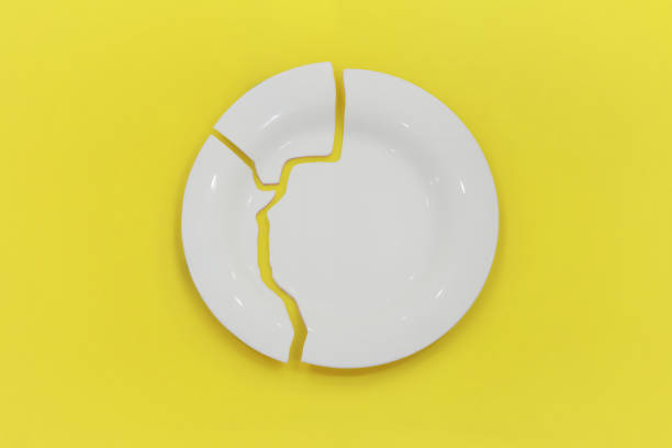 istock Top view on broken circle white plate on yellow background. The plate broke into three pieces. 1413886638