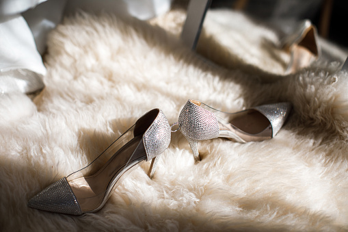 Wedding shoes and ring stand on the floor near the mirror.