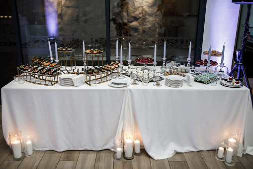 Rows of desserts and various snacks on the wedding table with candles