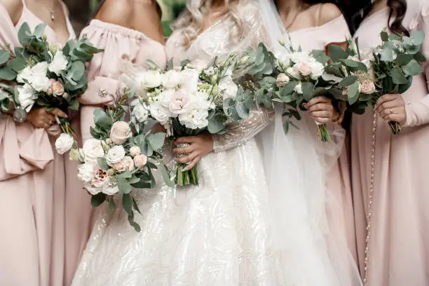 Photo of Bride with bridesmaids with flowers stand in a row