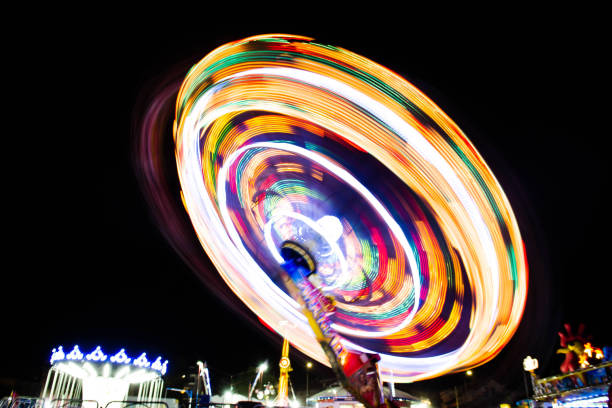 カルーセル、チルト・ア・ワールが動き、露出が広がります。カーニバルの暖かい夏の夜。サーカス。光の塗装効果を持つルナパーク長時間露光 - ferris wheel wheel blurred motion amusement park ストックフォトと画像