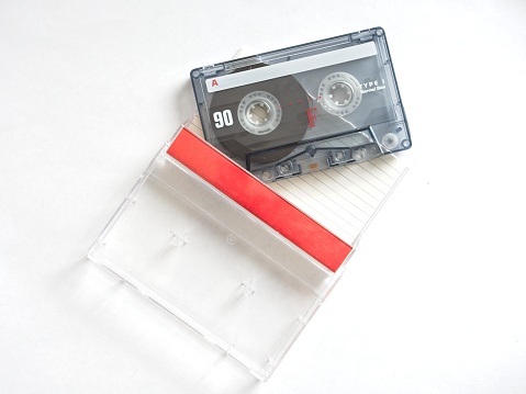 An audio cassette tape used for recording music or voice, a technology staple in the 1970s and 1980s. Magnetic tape cartridge for use in a tape deck or boom box. Ninety minute tape length required flipping of the tape shown with case and card for writing down recordings included.